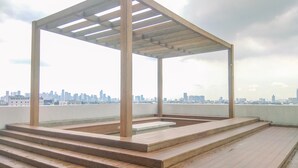Eine hölzerne Pergola auf einer Dachterrasse mit Stadtansicht im Hintergrund.