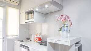 Una cocina moderna con armarios blancos, microondas integrado y dispensador de agua.