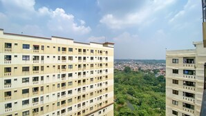 Un edificio residencial alto con varios balcones y vistas a un paisaje urbano y zonas verdes.