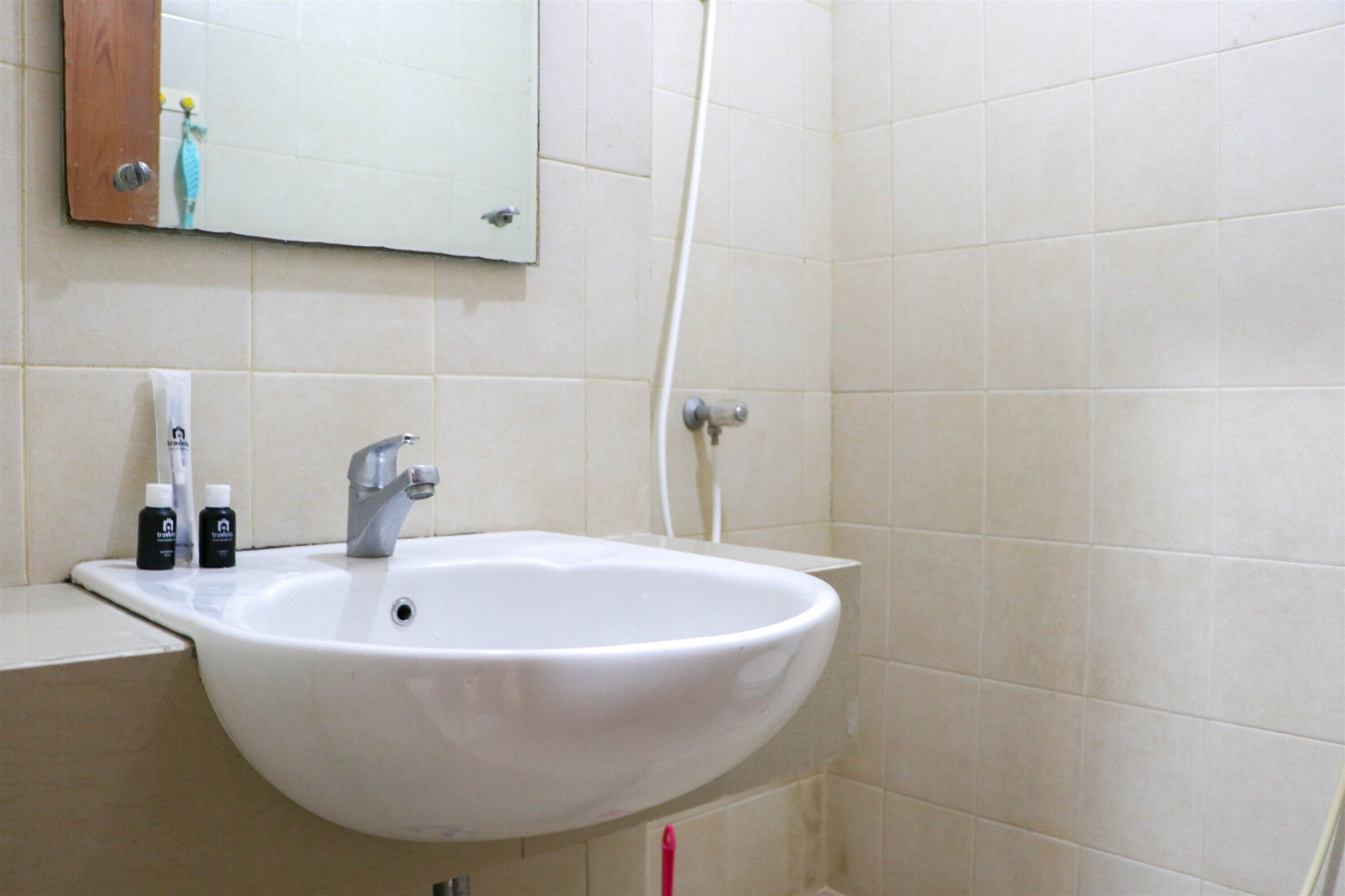 Baño con lavamanos blanco, espejo y ducha.