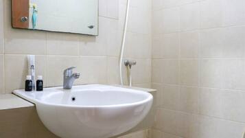 Baño con lavamanos blanco, espejo y ducha.