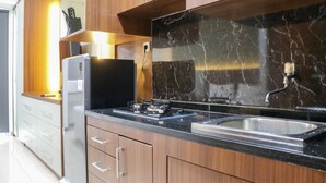 Una cocina moderna con armarios de madera, un protector contra salpicaduras de mármol negro, un lavamanos de acero inoxidable y una estufa a gas empotrada.