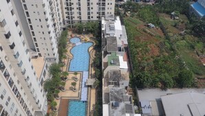 Un edificio alto con múltiples balcones, una piscina y un jardín ajardinado.