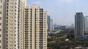 Un edificio residencial alto con varios balcones y una vista de la ciudad de fondo.