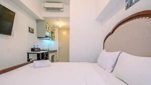 A hotel room with a bed, a desk with a computer, and a kitchenette. - Compact And Nice Studio Tokyo Riverside Pik 2 Apartment (Teluknaga)