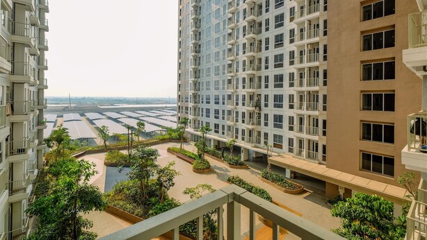 A high-rise residential building with multiple balconies and a landscaped courtyard. - Compact And Nice Studio Tokyo Riverside Pik 2 Apartment (Teluknaga)