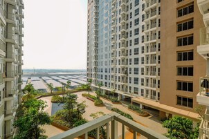 Um edifício residencial alto, com várias varandas e um pátio ajardinado.