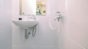 A bathroom with a white sink, a mirror, and a shower. - Compact And Nice Studio Tokyo Riverside Pik 2 Apartment (Teluknaga)