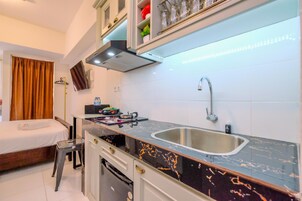 Quarto de hotel pequeno com cozinha compacta, cama e banheiro.