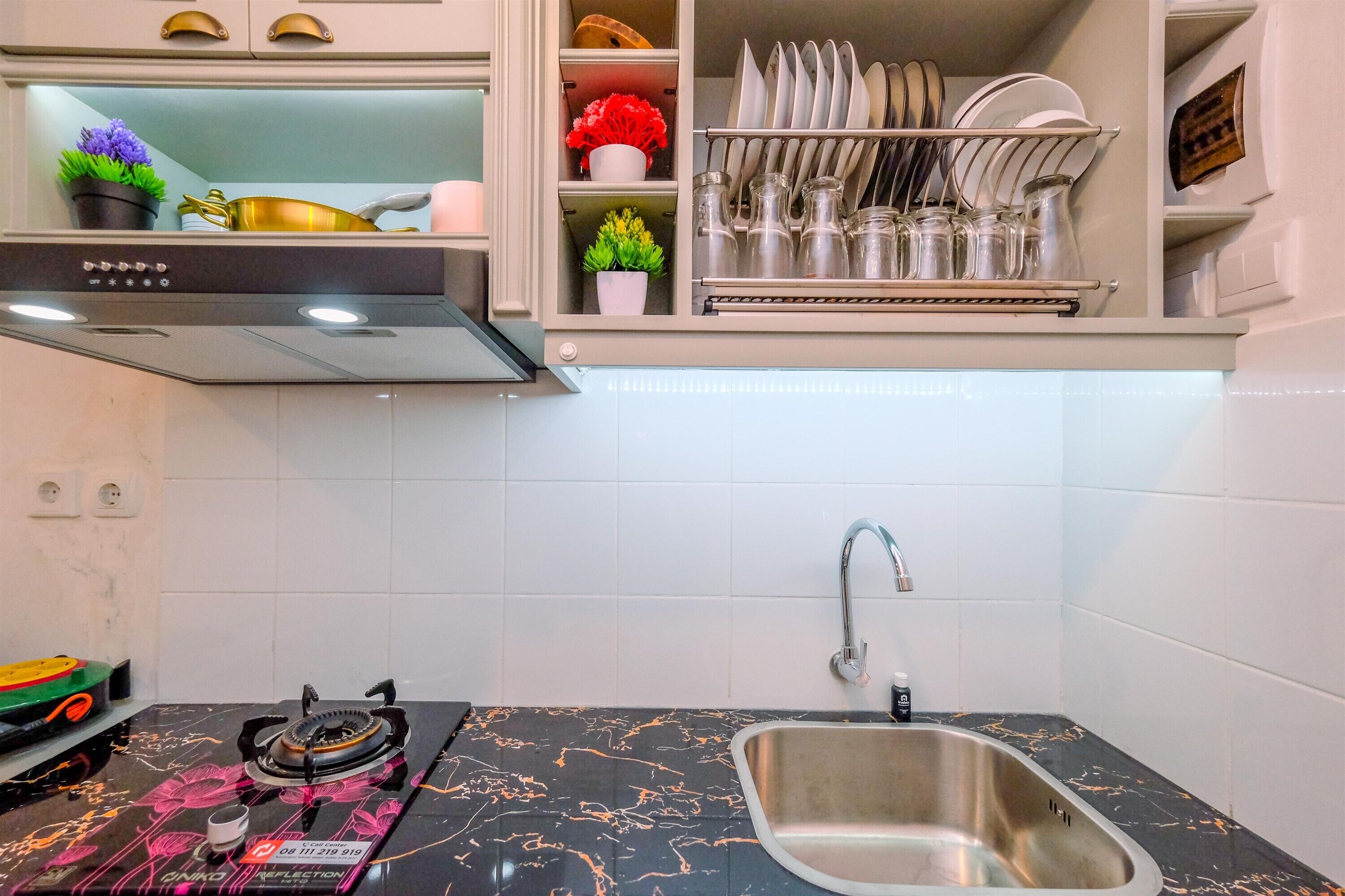 A kitchen with a black countertop, stainless steel sink, and a dish rack above the sink.