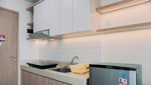 A modern kitchen with a built-in stove, sink, and stainless steel refrigerator. - Homey Living And Comfy Studio Apartment At B Residence (Pagedangan)