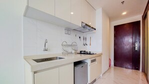 A modern kitchen with a stainless steel sink, a built-in dishwasher, and a gas stove. - Fully Furnished With Cozy Studio Sky House Bsd Apartment (Pagedangan)