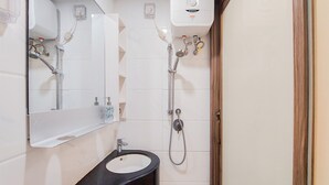 A bathroom with a black sink, a mirror, a handheld showerhead, and a wall-mounted heater. - Comfy Designed And Modern Studio At Sky House Bsd Apartment (Pagedangan)