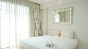 Ein Hotelzimmer mit einem großen Bett, einem Spiegel und durchsichtigen Vorhängen.