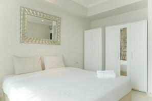 Relax in a serene space with a large bed, matching wardrobe, and elegant mirror.
