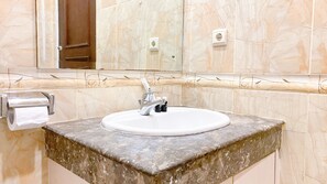 Bathroom features a large mirror above a sink with a paper towel dispenser and a door.