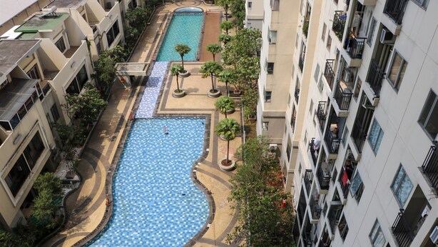 A residential building with a swimming pool, balconies, and surrounding greenery. - Compact And Elegant Studio Maple Park Sunter Apartment (Jakarta)
