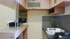 Eine kompakte Küche mit Holzschränken, einer Glasarbeitsplatte, einem Gasherd und einer gefliesten Rückwand.