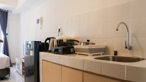 A compact kitchen with a refrigerator, a sink, and a stove. - Brand New Studio At Tokyo Riverside Pik 2 Apartment (Teluknaga)