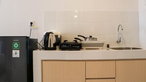 A kitchen with a refrigerator, stove, sink, and wooden cabinets. - Brand New Studio At Tokyo Riverside Pik 2 Apartment (Teluknaga)