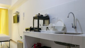 Una cocina moderna con azulejos blancos, un lavamanos de acero inoxidable, encimera negra y cortina amarilla.
