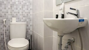 Un baño con inodoro, lavamanos y espejo.