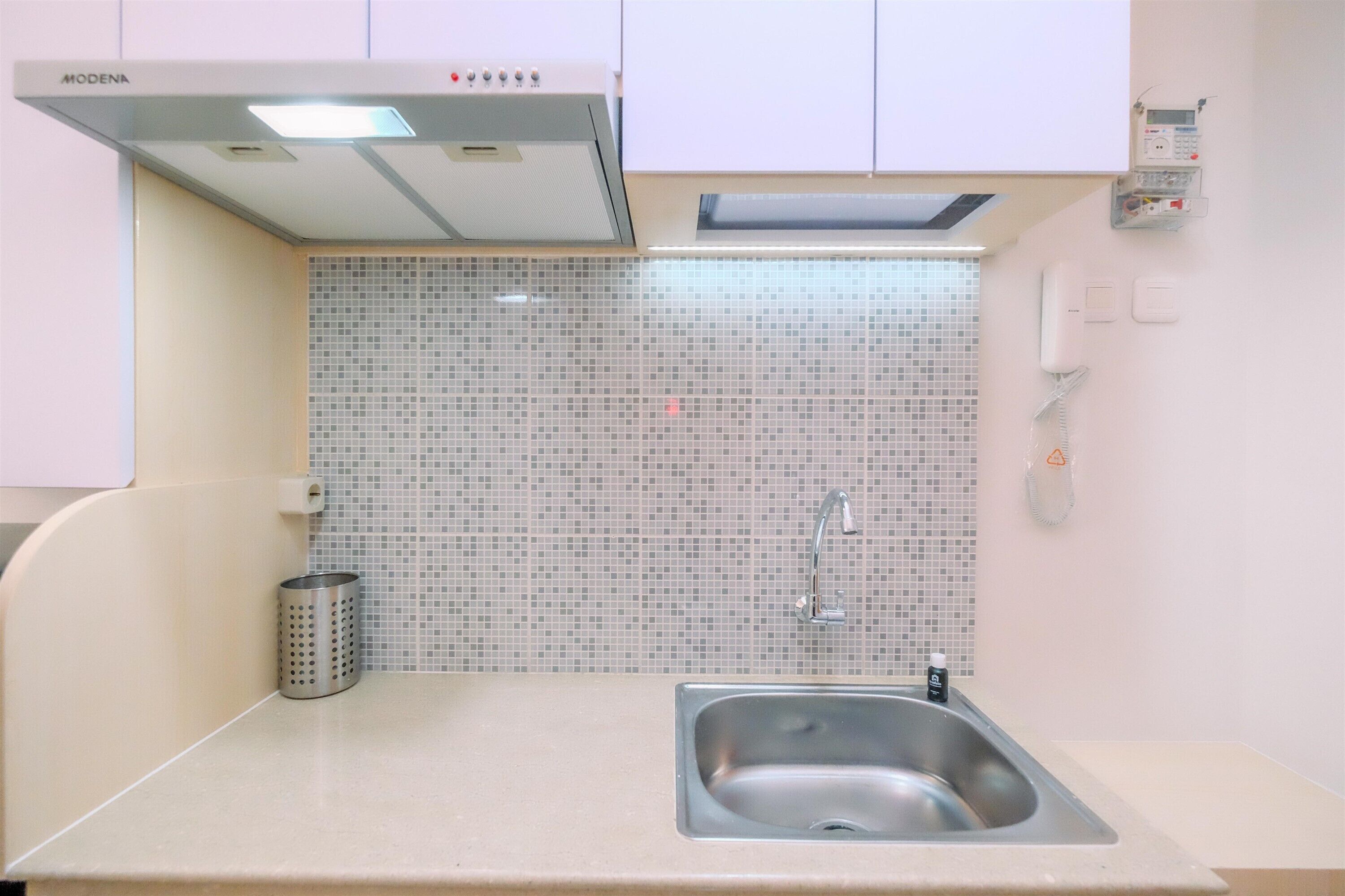 Una cocina con un lavamanos de acero inoxidable, una campana extractora moderna y un salpicadero de azulejos.