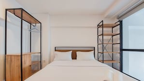 Un dormitorio con cama, armario de madera y estanterías empotradas.