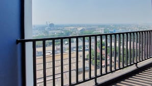 Vista desde un balcón con barandilla metálica, que muestra un paisaje urbano con edificios y calles.