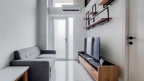 Una sala de estar moderna con un sofá, televisor y un mueble de madera.
