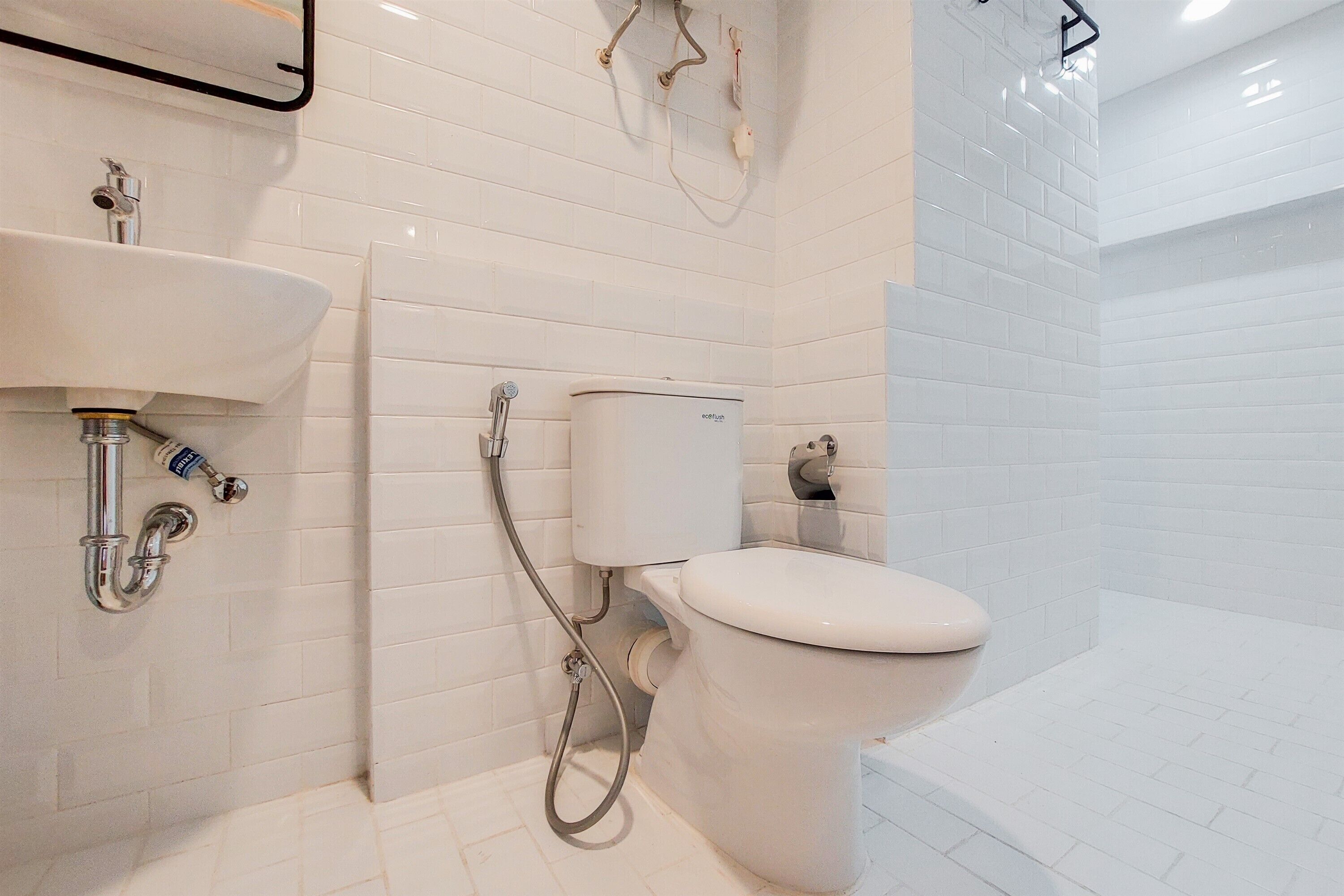 Un bagno moderno con lavandino, vaso e zona doccia, tutti bianchi.