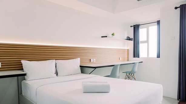 Moderni hotellihuone, jossa on sänky, työpöytä ja tuoli.