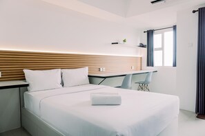 Une chambre d’hôtel moderne, équipée d’un lit, d’un bureau et d’une chaise.