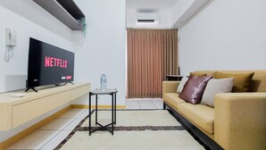 Una sala de estar moderna con un televisor de pantalla plana, un sofá, una mesita y una cortina.