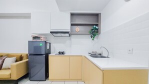 Una cocina compacta con refrigerador, lavamanos y una pequeña encimera.