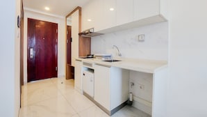 Una cocina compacta con armarios blancos, horno integrado y lavamanos.