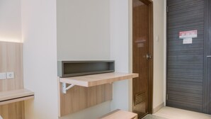 A modern room with a built-in TV shelf, a wooden door, and a small wooden table. - Homey And Warm Studio Amazana Serpong Apartment (South Tangerang)