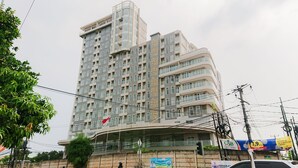 A multi-story building with a curved facade, balconies, and a flag. - Homey And Warm Studio Amazana Serpong Apartment (South Tangerang)
