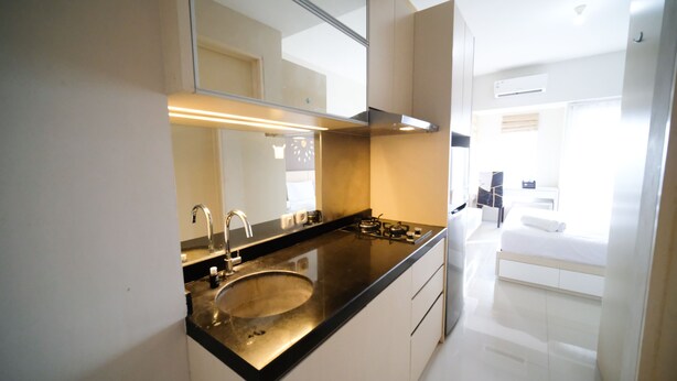Une salle de bain moderne avec un lavabo, un miroir et une vue sur la chambre.