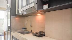 A modern kitchen with a built-in stove, a sink, and a stainless steel range hood. - Homey And Simply Look Studio Belmont Residence Puri Apartment (Jakarta)