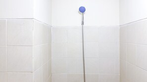 A shower with a blue head, a metal hose, and white tiled walls. - Homey And Simply Look Studio Belmont Residence Puri Apartment (Jakarta)