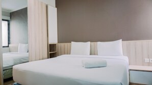 A hotel room with a large bed, a bedside table, and a wardrobe. - Best Deal And Comfortable 2Br Asatti Apartment (Pagedangan)
