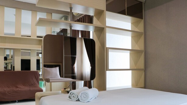 A modern hotel room with a large bed, a seating area, and a built-in wardrobe.