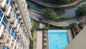 A high-rise building with balconies, a swimming pool, and a river.