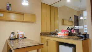 Uma cozinha compacta com bancada, pia, uma pequena geladeira e uma mesa de jantar.