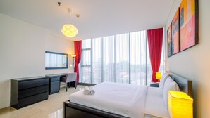 Une chambre d’hôtel moderne avec un grand lit, un bureau et une chaise. Il y a une fenêtre avec des rideaux rouges et une vue sur la ville.