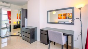 Une chambre d’hôtel moderne équipée d’un bureau, d’une chaise et d’un grand miroir.