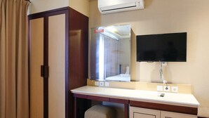 Habitación de hotel con escritorio, una silla, televisión montada en la pared y un equipo de aire acondicionado sobre el escritorio.