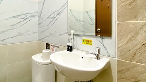 A bathroom with marble walls, a sink, a toilet, and a wooden cabinet. - Best Deal And Cozy Studio At Apartment Transpark Juanda Bekasi Timur (Bekasi)