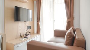 Ein modernes Zimmer mit Flachbildfernseher an der Wand, einem Schreibtisch inklusive Fernbedienung und einem Sofa.